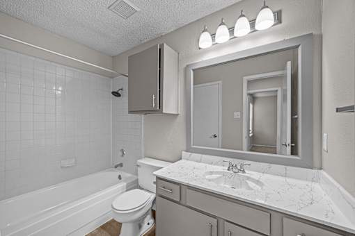 A white bathroom with a tub, toilet, and sink.