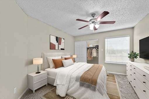 A bedroom with a bed, nightstand, and a ceiling fan.
