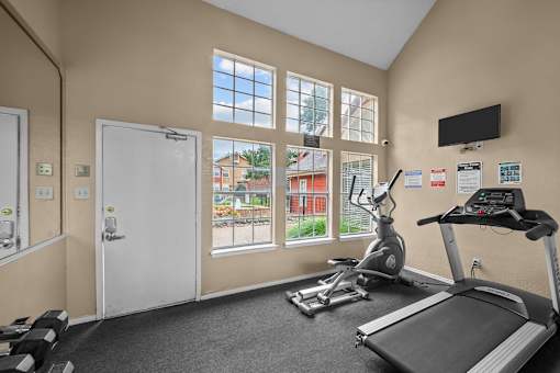 A gym room with a treadmill, exercise bike, and other equipment.