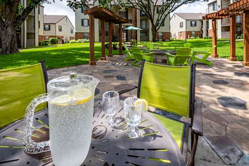 A table with a pitcher of lemonade and glasses on it.