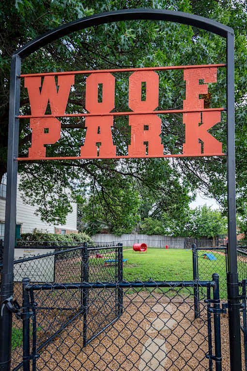 A black fence with a sign that says WOOF PARK.