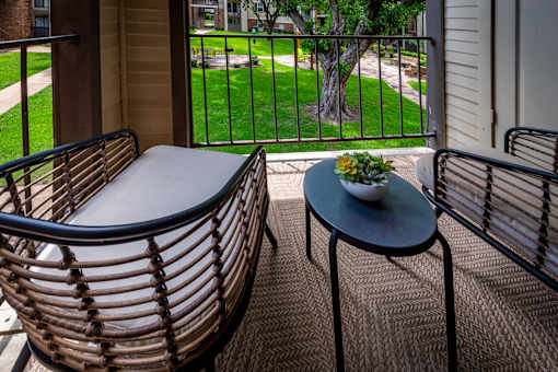 A table with a bowl of fruit on it sits on a patio.