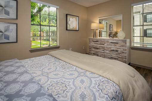 A bedroom with a bed, dresser, and window.