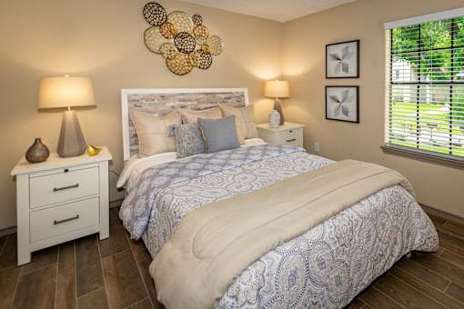 A bedroom with a large bed and a white nightstand with two lamps.