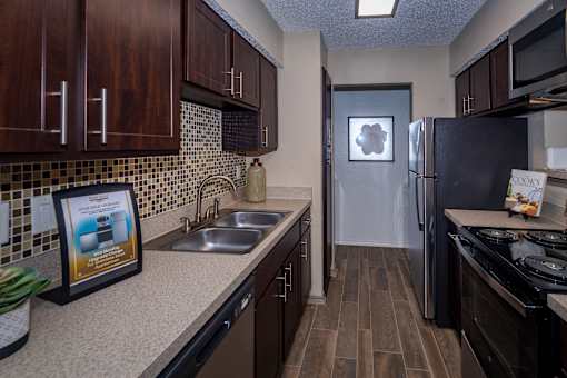A kitchen with a fridge, stove, and sink.