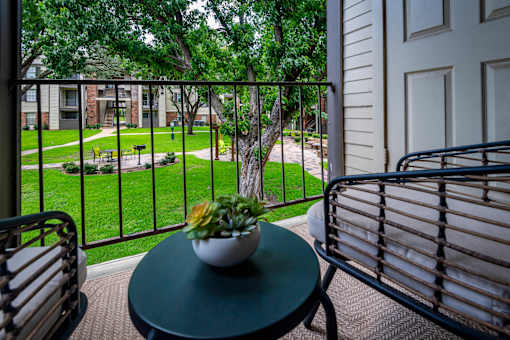 A small table with a plant on it sits on a balcony.