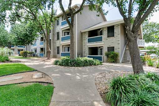 an apartment building with a walkway and trees in front of it