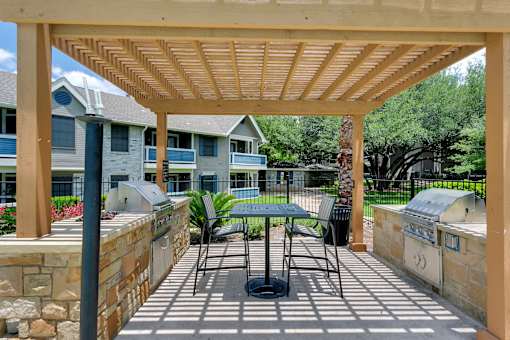 a patio with a table and chairs under a pergola
