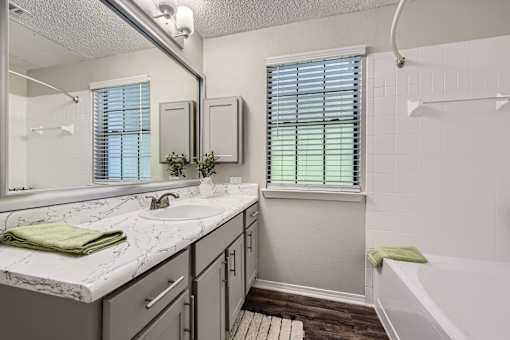 A bathroom with a marble countertop and a window with blinds.
