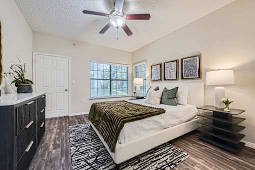 A bedroom with a bed, dresser, and a ceiling fan.