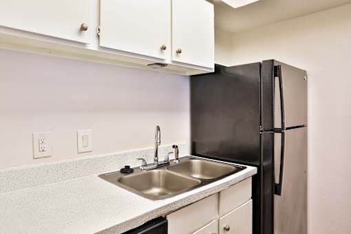 A kitchen with a black refrigerator and white cabinets.