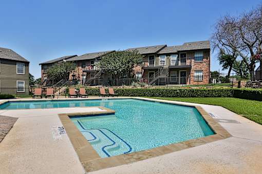 A swimming pool in front of a building with a clear blue sky.