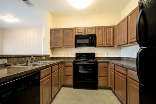 A kitchen with black appliances and wooden cabinets.
