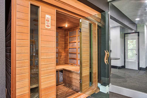 A wooden sauna with a glass door is open.