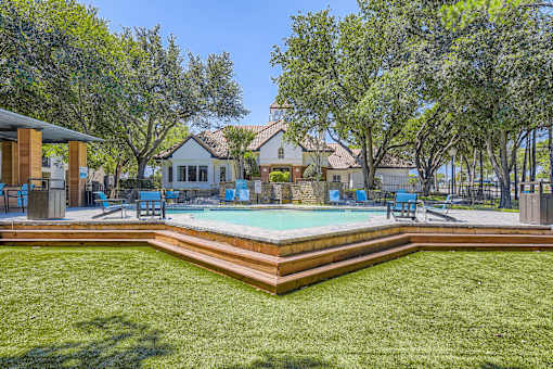 A pool surrounded by a grassy area and trees.