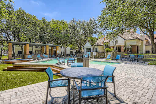 A patio with a table and chairs overlooking a pool.