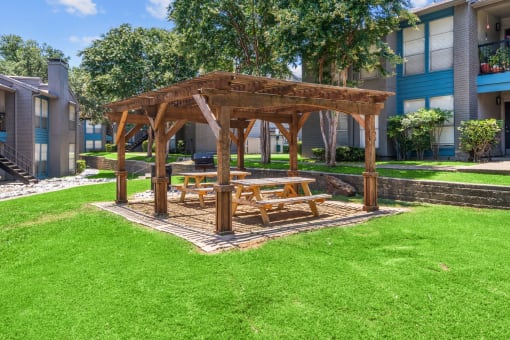a wooden gazebo with a picnic table in the middle of a grassy area  at Vesper, Dallas, Texas