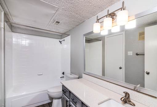 A white bathroom with a toilet, sink, and mirror.