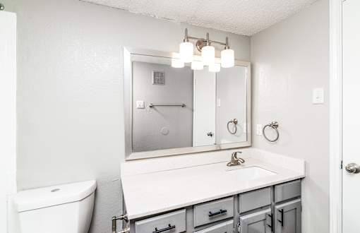A white bathroom with a toilet, sink, and mirror.