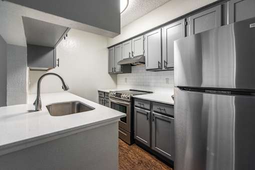 A modern kitchen with a stainless steel refrigerator and a white countertop.