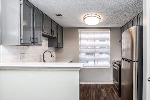 A kitchen with a white counter top and a stainless steel refrigerator.