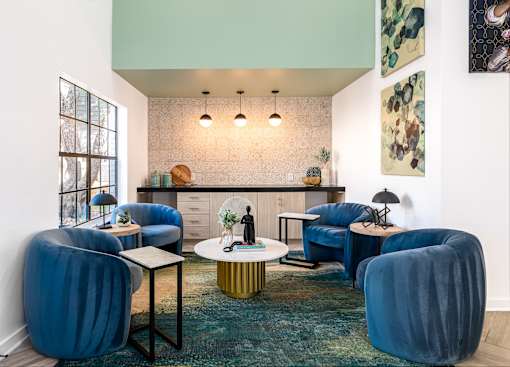 A room with blue chairs and a green rug.