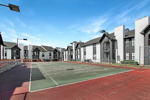 A tennis court is surrounded by houses.