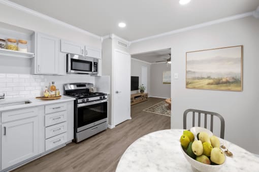 a kitchen with white cabinets and a white marble table with a bowl of fruit on it  at Sunset Heights, San Antonio, TX, 78209