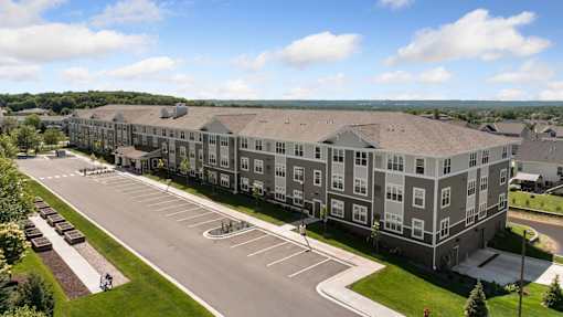 A large apartment complex with a parking lot in front.