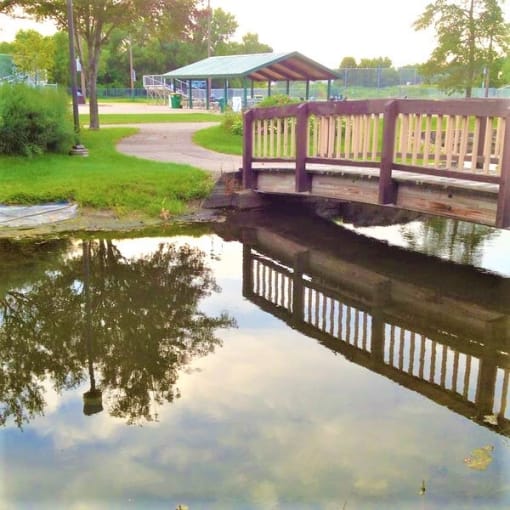 a bridge over a body of water with a picnic shelter in the background