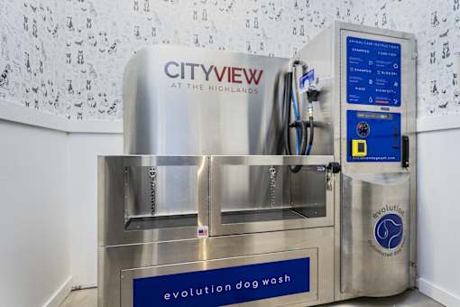 A machine with a blue label that says "evolution dog wash" is in front of a wall with a pattern of dog paw prints.