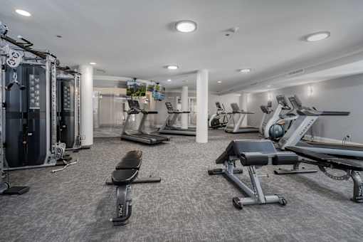 A spacious gym with a variety of equipment including treadmills, stationary bikes, and weight machines.