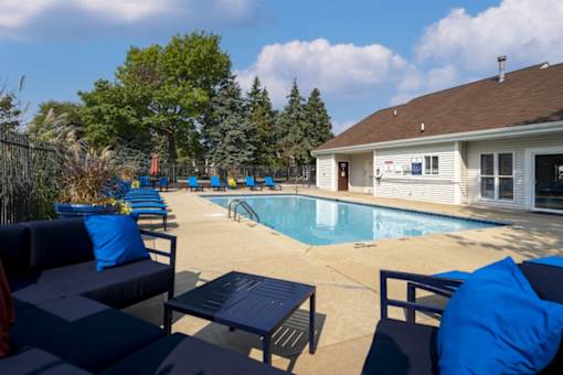 A pool area with blue cushions and a white building in the background.