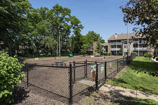 A black fence surrounds a playground with a sign on it.