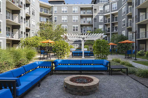 A patio with a fire pit and blue seating.