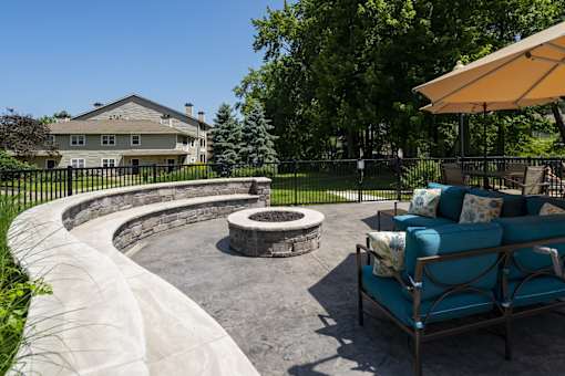 A patio with a fire pit and a blue couch.