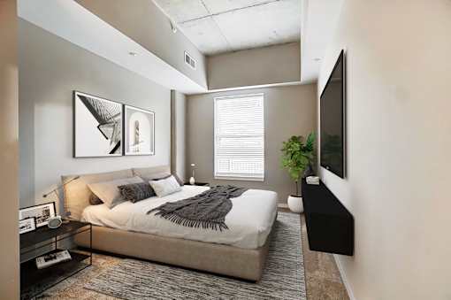A bedroom with a bed, a nightstand, a plant, and a TV.