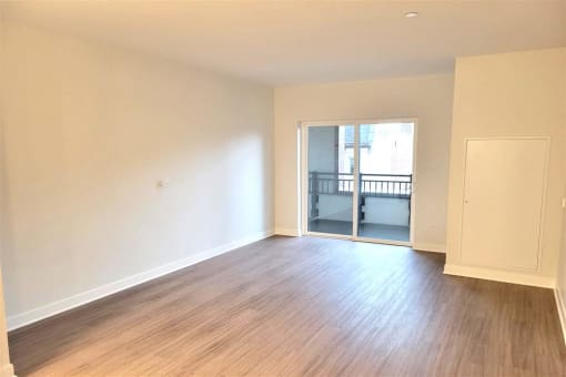 an empty living room with wood floors and a balcony
