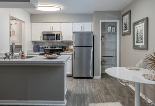 A modern kitchen with a refrigerator, microwave, oven, and sink.