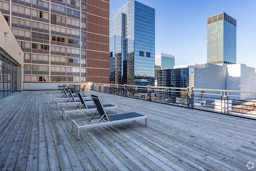 A wooden deck with chairs and a table with a city skyline in the background.