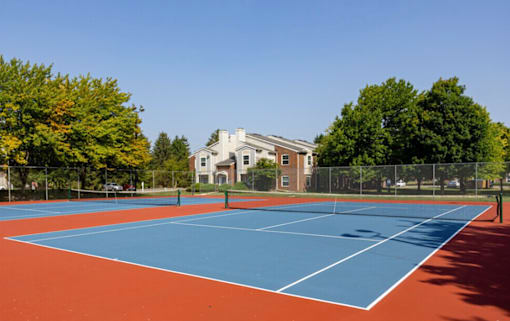 A tennis court with a red and blue surface and white lines.