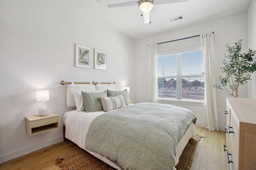 A bedroom with a bed, nightstand, and a plant. at Park South Apartments, Austin