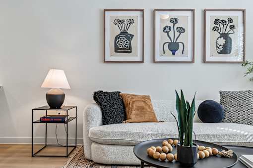 A living room with a white couch, a lamp, and three framed pictures on the wall.