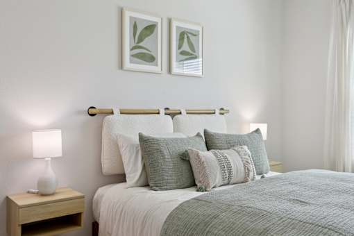 A bed with a white comforter and a lamp on a nightstand. at Park South Apartments, Austin, Texas