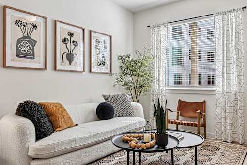 A living room with a white couch, a coffee table, and three framed pictures on the wall.
