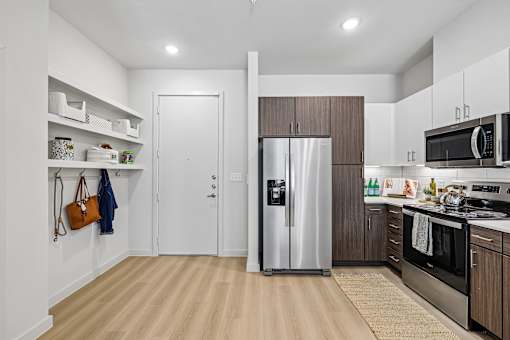 A kitchen with a refrigerator, microwave, and oven.