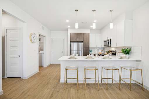 A kitchen with a bar area and four stools. at ThreeTwenty at the Vybe Apartments, Kyle