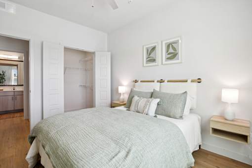 A bedroom with a bed, two lamps, and two framed pictures on the wall. at Park South Apartments, Austin, 78748