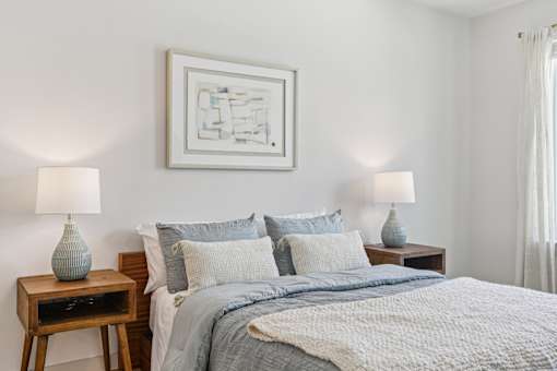 A bedroom with a bed, two lamps, and a painting on the wall. at ThreeTwenty at the Vybe Apartments, Kyle