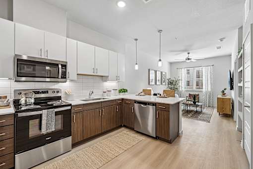 A modern kitchen with a stove, microwave, and oak cabinets.